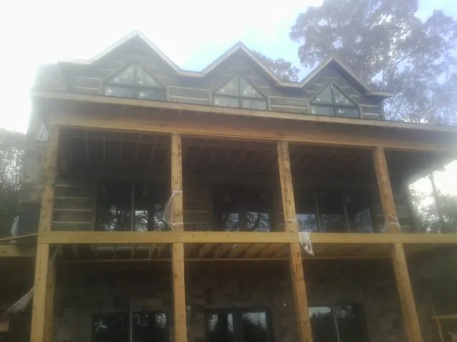 Dormers and porch framing on a large log home under construction — Roof Coating work by our crew in Fair Haven